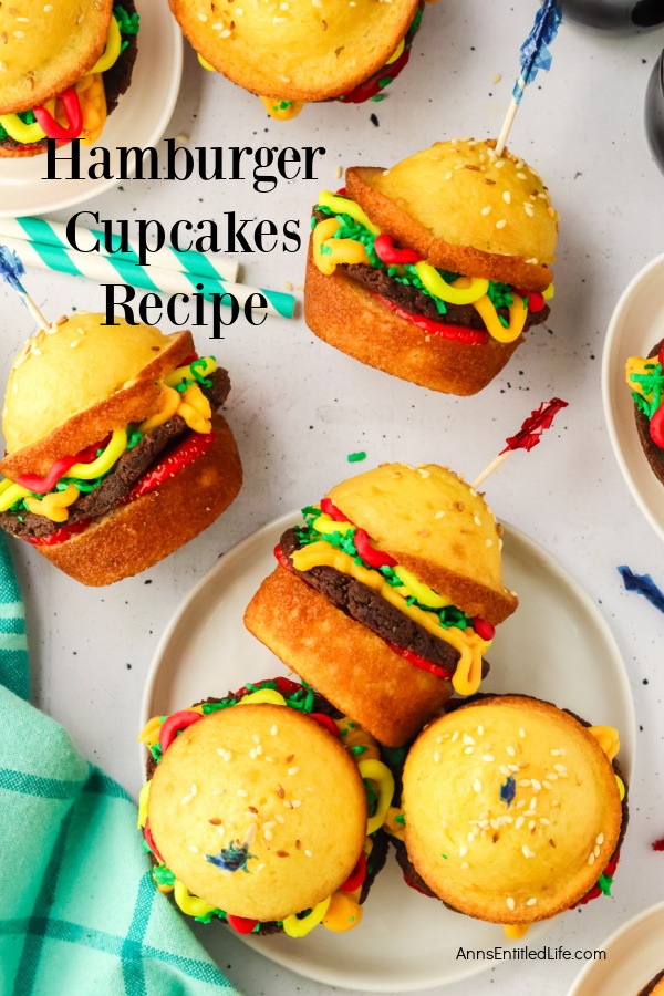 Seven cupcakes assembled to look like hamburgers sitting on white plates and on a white countertop