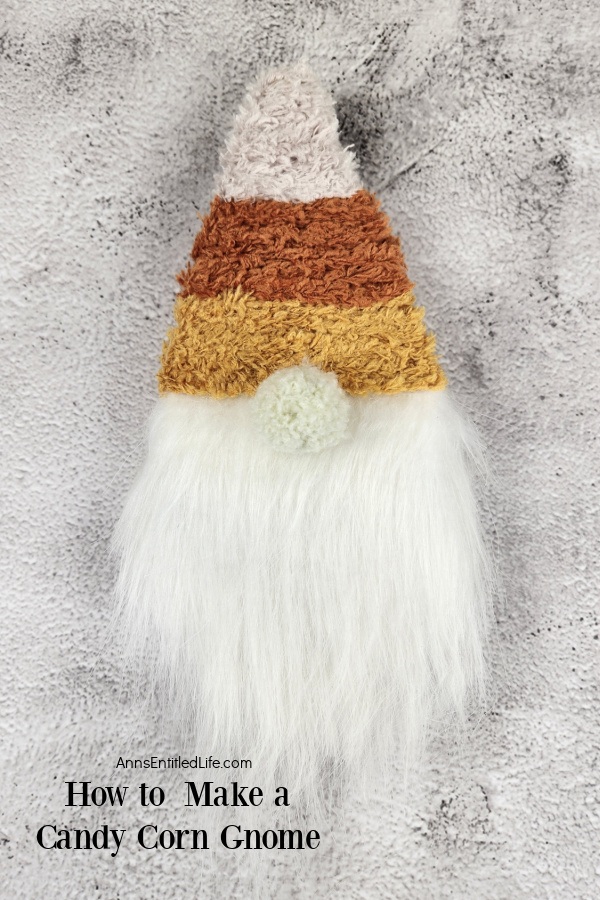 a candy corn gnome set against a light grey background