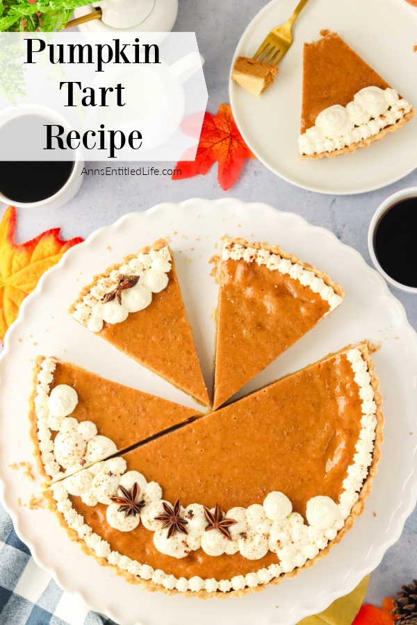 Overhead view of a pumpkin tart, one piece removed, two others are cut on the white serving dish. The removed piece of pumpkin tart is on a white plate in the upper right.