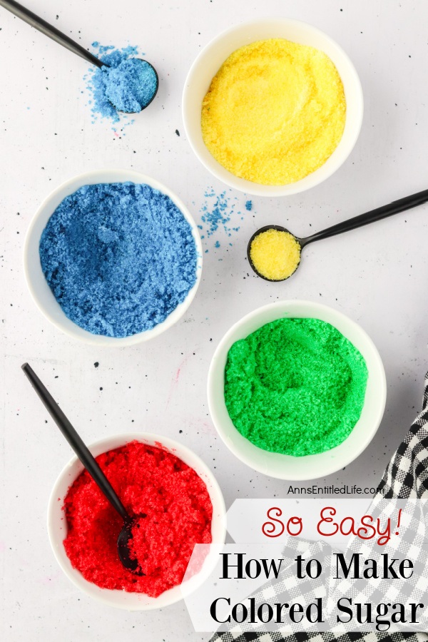 Four small white boals have colored sugar in them: red, green, yellow, and blue. There are also three spoons on the surface.