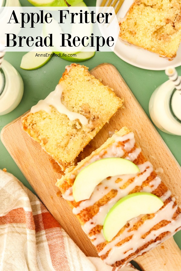 An overhead view of a cut apple fritter bread on a wooden cutting board. There is a piece of cut apple fritter bread on a white plate in the upper right, a white and red dishtowel in the lower left.