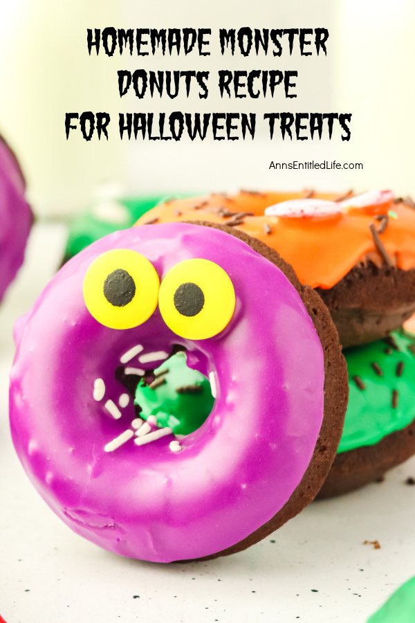 Closeup view of a chocolate donut with purple glaze and colorful eyes, there are two similarly decorated donuts behind it