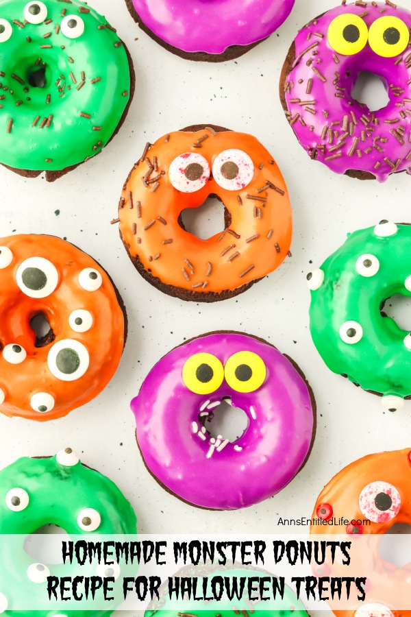 An overhead view of chocolate donuts decorated in Halloween colors and decorations on a white surface