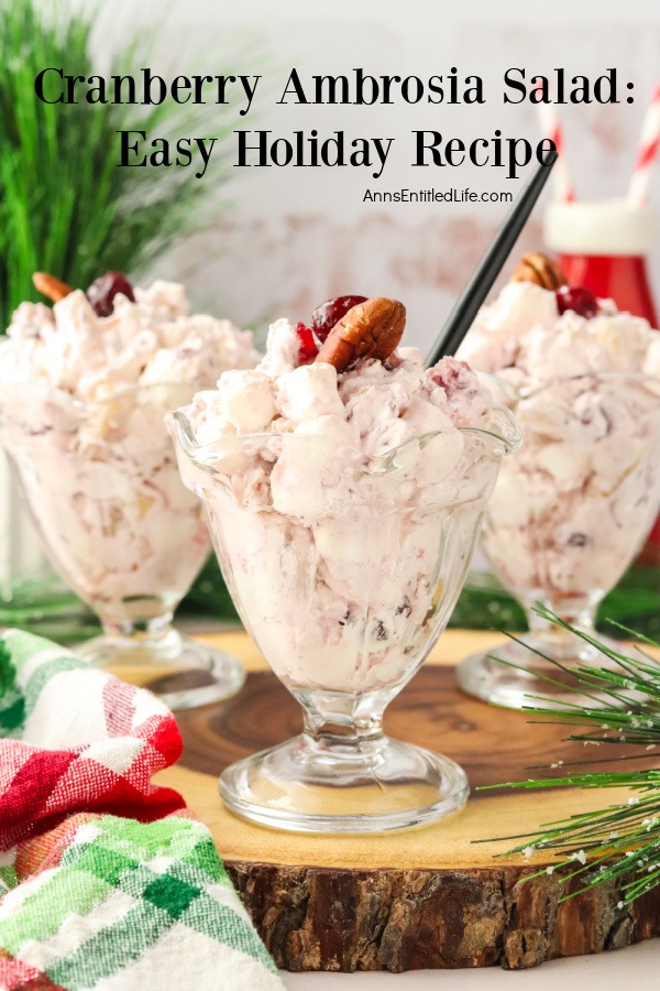 Cranberry Ambrosia Salad: Easy Holiday Recipe Three parfait glasses filled with cranberry ambrosia salad set on top of a wooden charger.