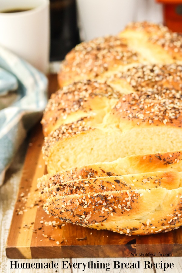 Overhead view of a loaf of homemade everything bread on a wire rack a cutting board, several pieces are sliced away