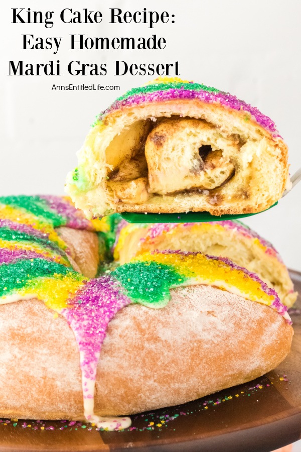 A close up side view of a king cake on a wooden platter. There is a piece being lifted from the cake below.