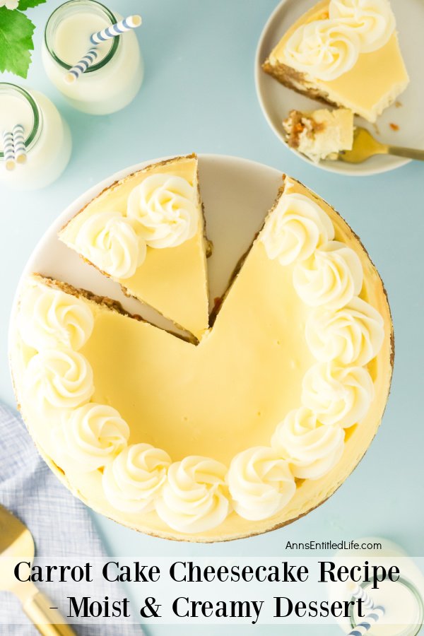 An overhead view of a carrot cake cheesecake with a piece removed. That piece is on a white plate in the upper right, there are two bottles of milk in the upper left