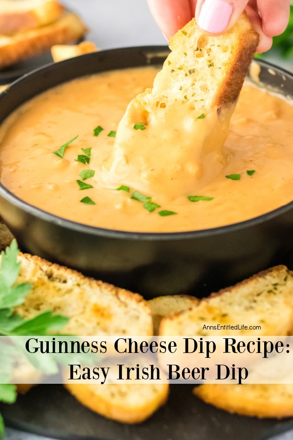 A black bowl filled with Guinness cheese dip, surrounded by toasted bread. A piece of bread is being dipped into the dip below.