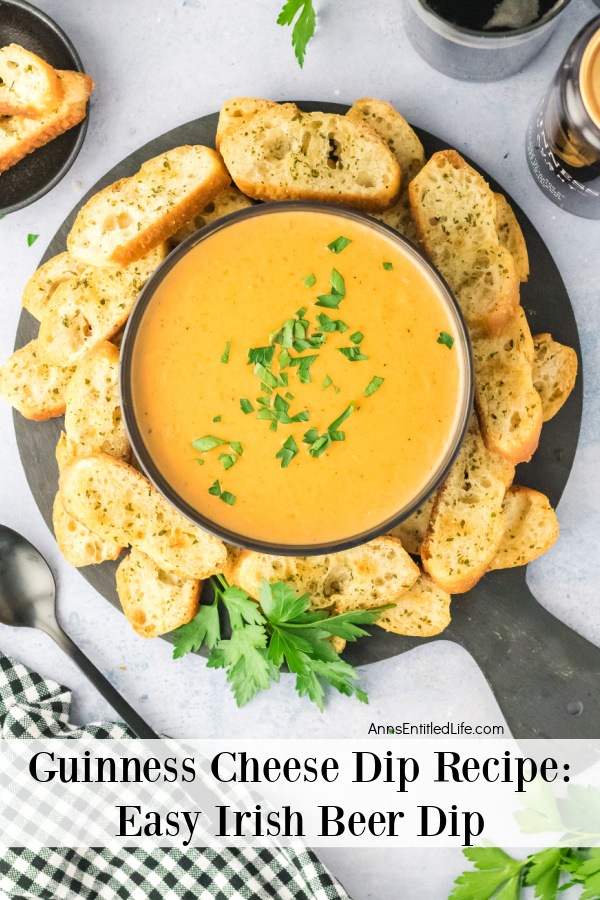 Overhead view of a bowl of Guinness cheese dip surrounded by toasted bread slices on a wooden serving board