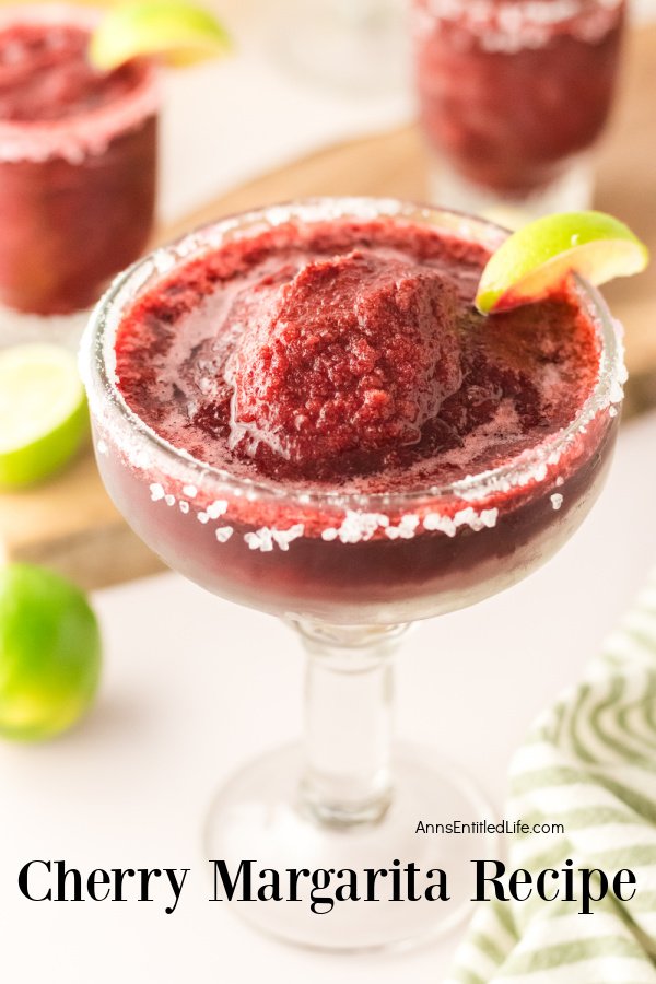 Overhead photo of a frozen cherry margarita in a margarita glass, there are two small filled cocktail glasses sitting on a cutting board above