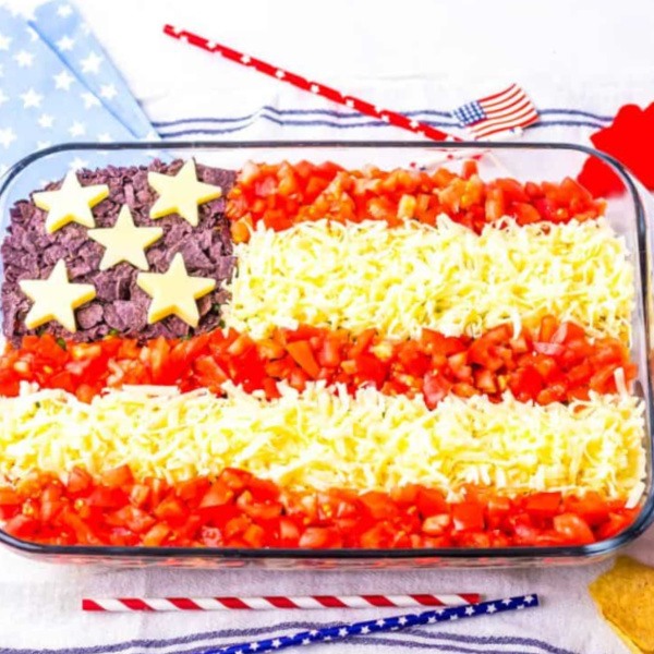 American Flag Taco Dip Recipe – the ultimate festive 4th of July appetizer! Layered with salsa, cheese, taco flavors, and refried beans for a fun red, white, and blue display.