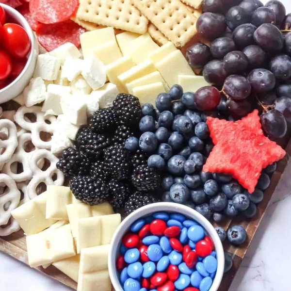 Create a fun patriotic charcuterie board perfect for kids! This red, white, and blue grazing platter is loaded with strawberries, blueberries, marshmallows, cheese, and sweet treats.  A fun, festive 4th of July party platter everyone will love.