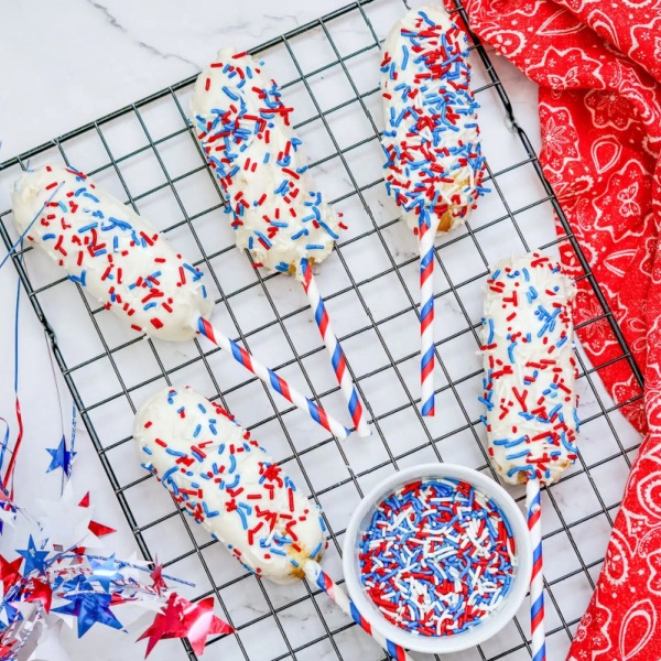 Easy Patriotic Chocolate Covered Twinkies dipped in creamy white chocolate and decorated with vibrant red, white, and blue sprinkles and candy. A crowd-pleasing, no-bake treat perfect for Independence Day parties.